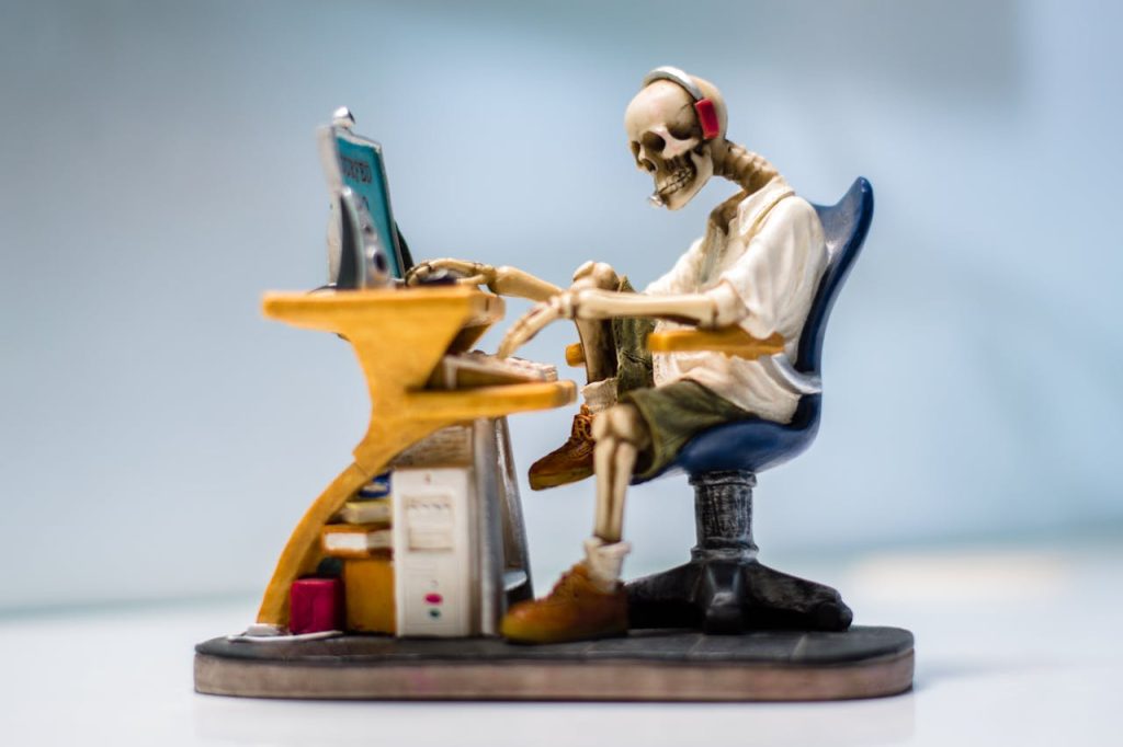 Crafting Captivating Headlines: Your awesome post title goes here A quirky skeleton figurine wearing headphones sits at a desk with a computer, symbolizing burnout.